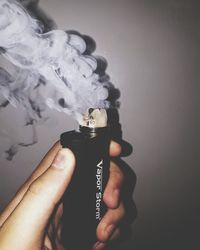 Close-up of hand holding cigarette against white background