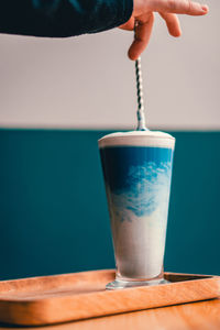 Close-up of hand holding drink on table