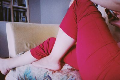 Low section of woman sitting on sofa at home