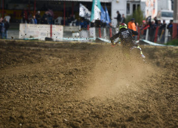 Unrecognized athlete riding a sports motorbike and muddy wheel on a motocross racingt