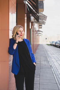 Portrait of young woman standing against building