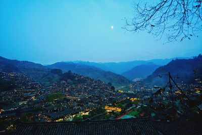 Illuminated buildings in city against blue sky