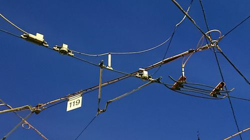 Low angle view of telephone pole against clear blue sky