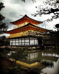 Traditional building by lake against sky