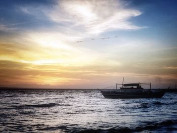 Boats in sea at sunset