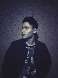 Portrait of young man looking away against wall