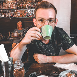Portrait of a young man drinking glass in restaurant