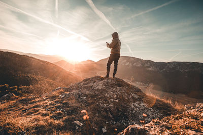 Man standing on mountain against sky during sunset