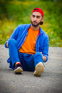 Portrait of young man sitting on road