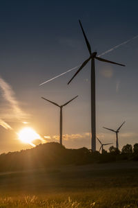 Windmill on field against sky during sunset