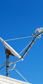 Low angle view of telephone pole against clear blue sky