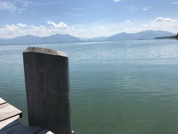 Wooden posts in lake against sky