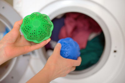Cropped hands of woman putting detergent in washing machine