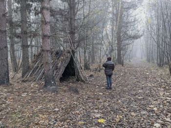 Rear view of woman standing on land in forest