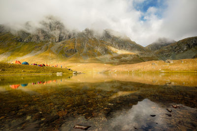 Tent on the shore of a mountain lake framed by rocky mountains. russia, arkhyz