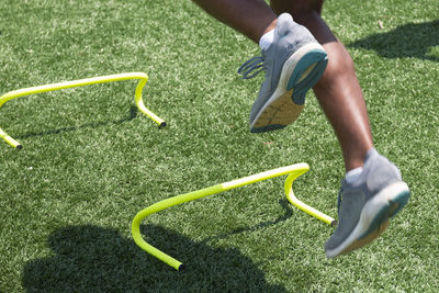 Male jumping over yellow mini hurdles close up with motion blur showing the speed of the drill.