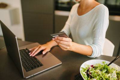 Midsection of woman using mobile phone while sitting on table