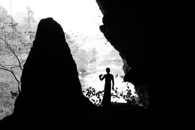 Low angle view of silhouette woman standing by rock against sky