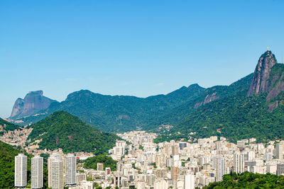 Aerial view of townscape by mountains against clear blue sky