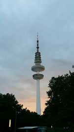 Low angle view of communications tower against cloudy sky