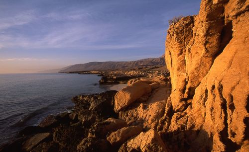 Rock formations by sea against sky