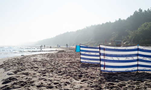 Deck chairs on beach against sky