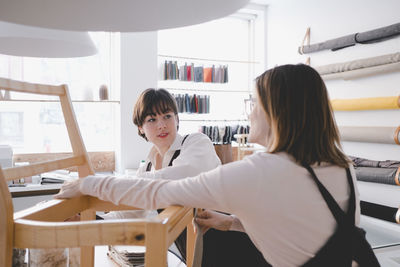 Female upholstery workers are working on chair in workshop