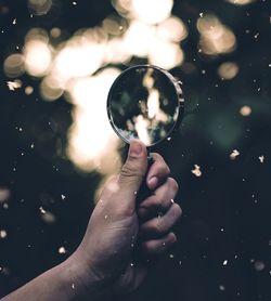 Cropped hand of man holding magnifying glass