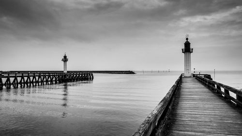 Lighthouse on pier by sea against sky