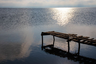 Pier over sea against sky during sunset