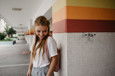 Young woman standing against wall