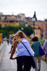 Rear view of woman walking against buildings in city