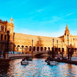 Boats in canal by buildings in city