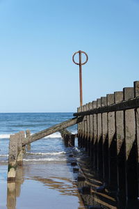 Pier over sea against clear blue sky