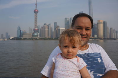 Portrait of man and baby girl with oriental pearl tower in background against sky