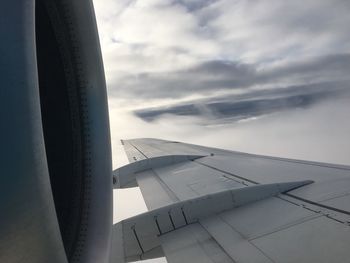 Cropped image of airplane flying over cloudscape against sky