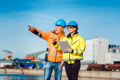 Friends standing with arms outstretched against sky