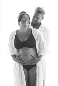 Portrait of young couple standing against white background