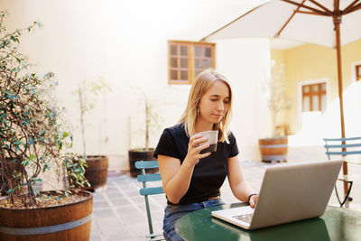 Smiling woman using laptop in cafe