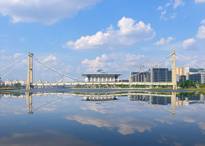 Bridge over river in city against cloudy sky