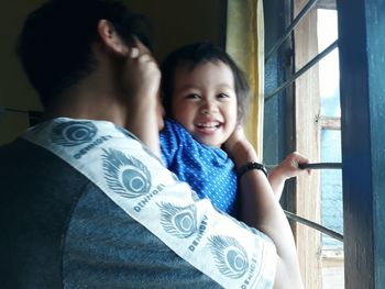 Portrait of cute boy with father by window at home