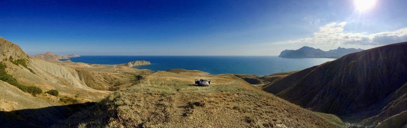 Panoramic view of sea and mountains against blue sky