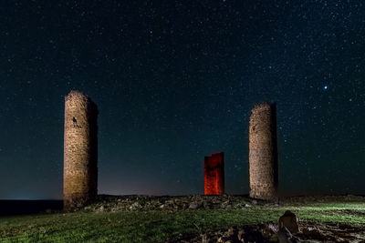 Low angle view of tower on field against sky at night