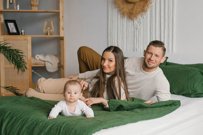 Portrait of beautiful young parents and a cute child looking into the camera and smiling while lying