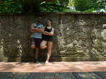 Full length of young couple standing against wall