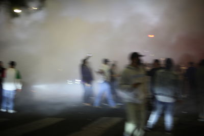 Blurred motion of people walking on road in city at night