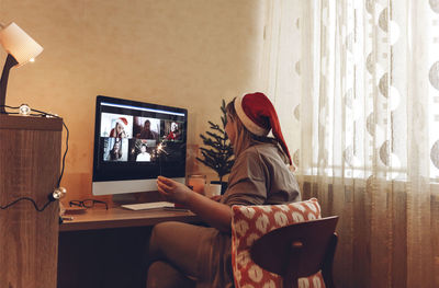 Rear view of woman sitting on sofa at home