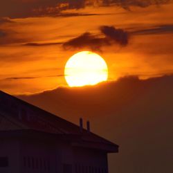 Silhouette built structure against orange sky