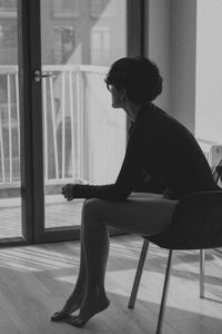 Side view of young man sitting on seat at home