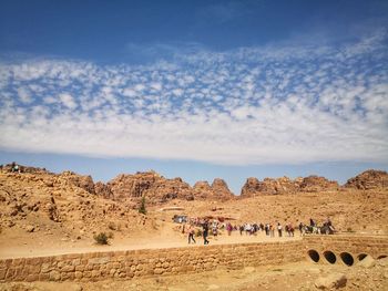 People on arid landscape against clear skies in petra